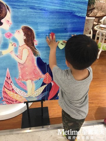 小帅哥很用心的把对妈妈的爱贴在爱心墙上